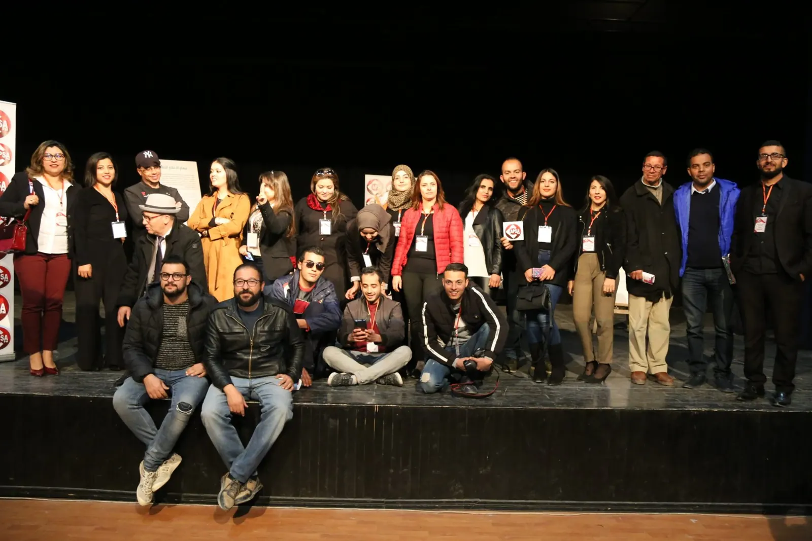 Groupe réuni sur scène lors d'un événement de Radio Capsa FM, devant les kakémonos de la radio
